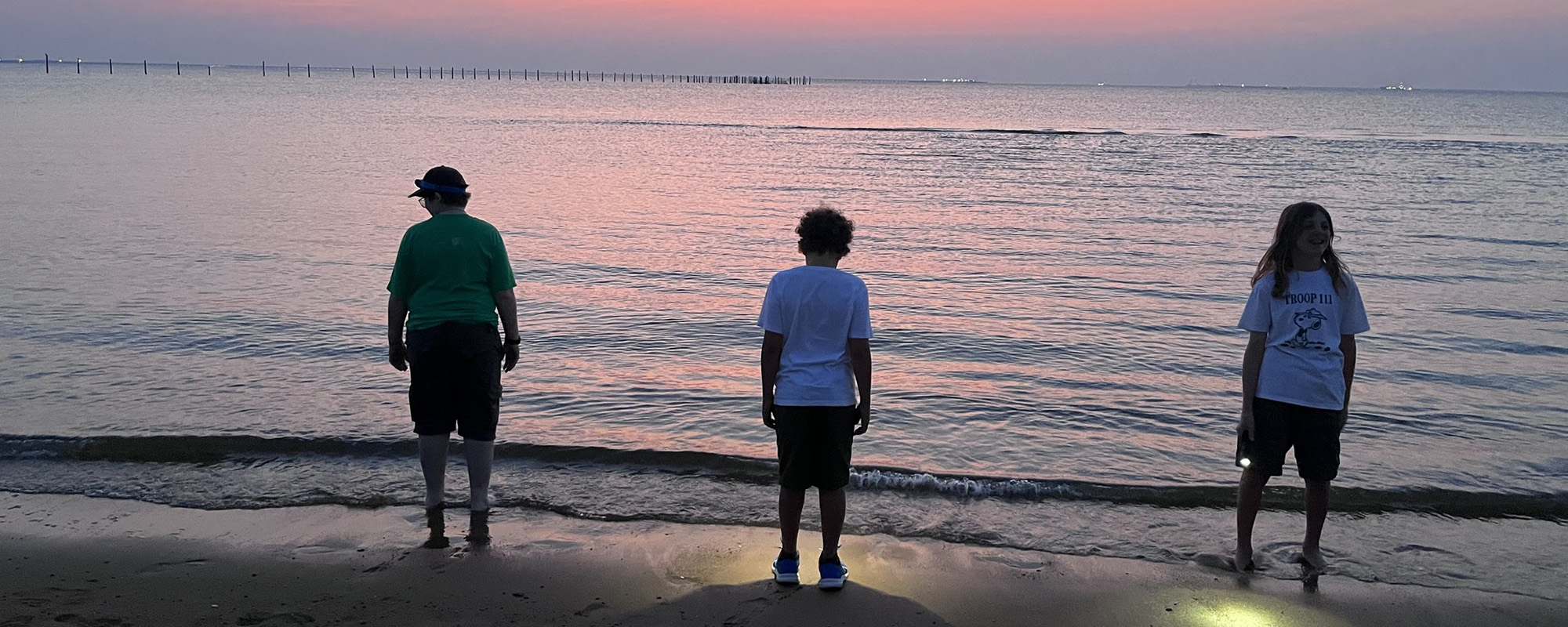 Three scouts standing on the beach of the Chesapeake Bay