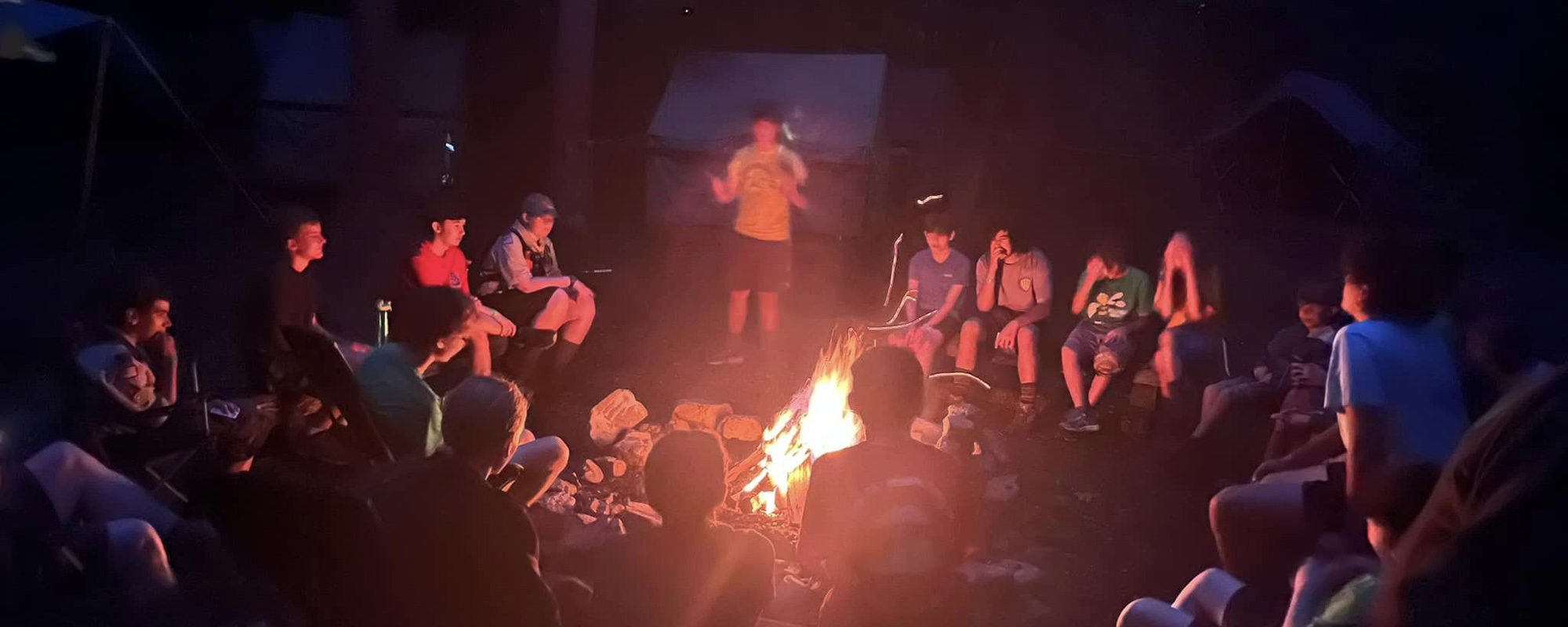 Troop 111 sitting around the campfire back at their site during summer camp